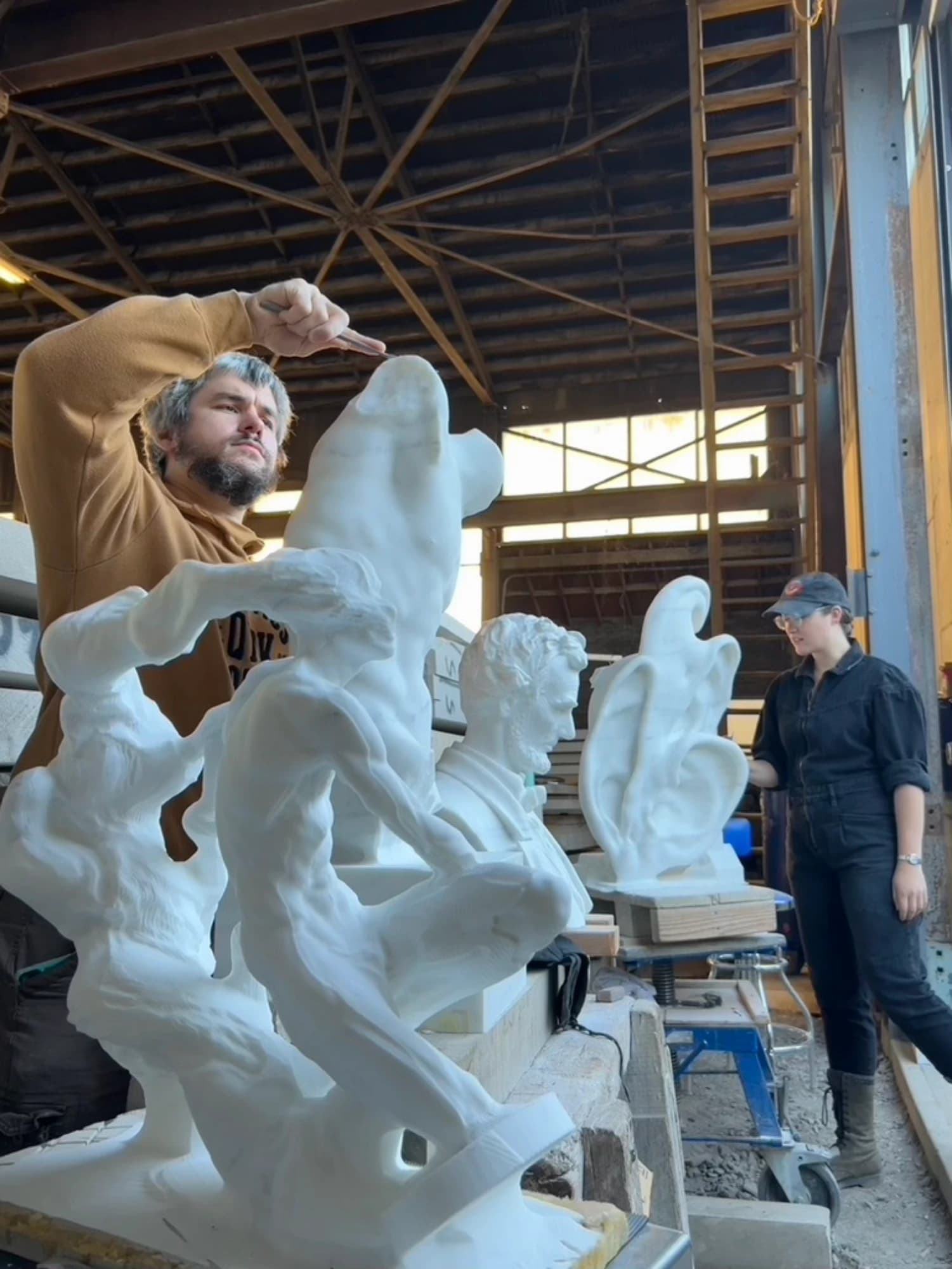 Two carvers finishing marble figures in the workshop